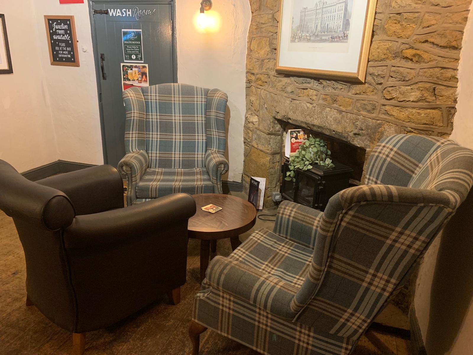 Comfy armchairs by the fireplace at The Hollybush Inn